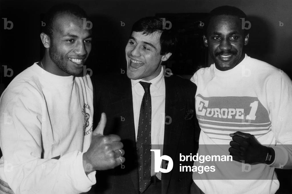 Left French Boxer Freddy Skouma And Right American Boxer Mccallum (World Champion Wba Super Welters During A Common Press Conference At A Grand Parisian Hotel With At The Centre Louis Acaries Match Organizer On October 20, 1986 (b/w photo)