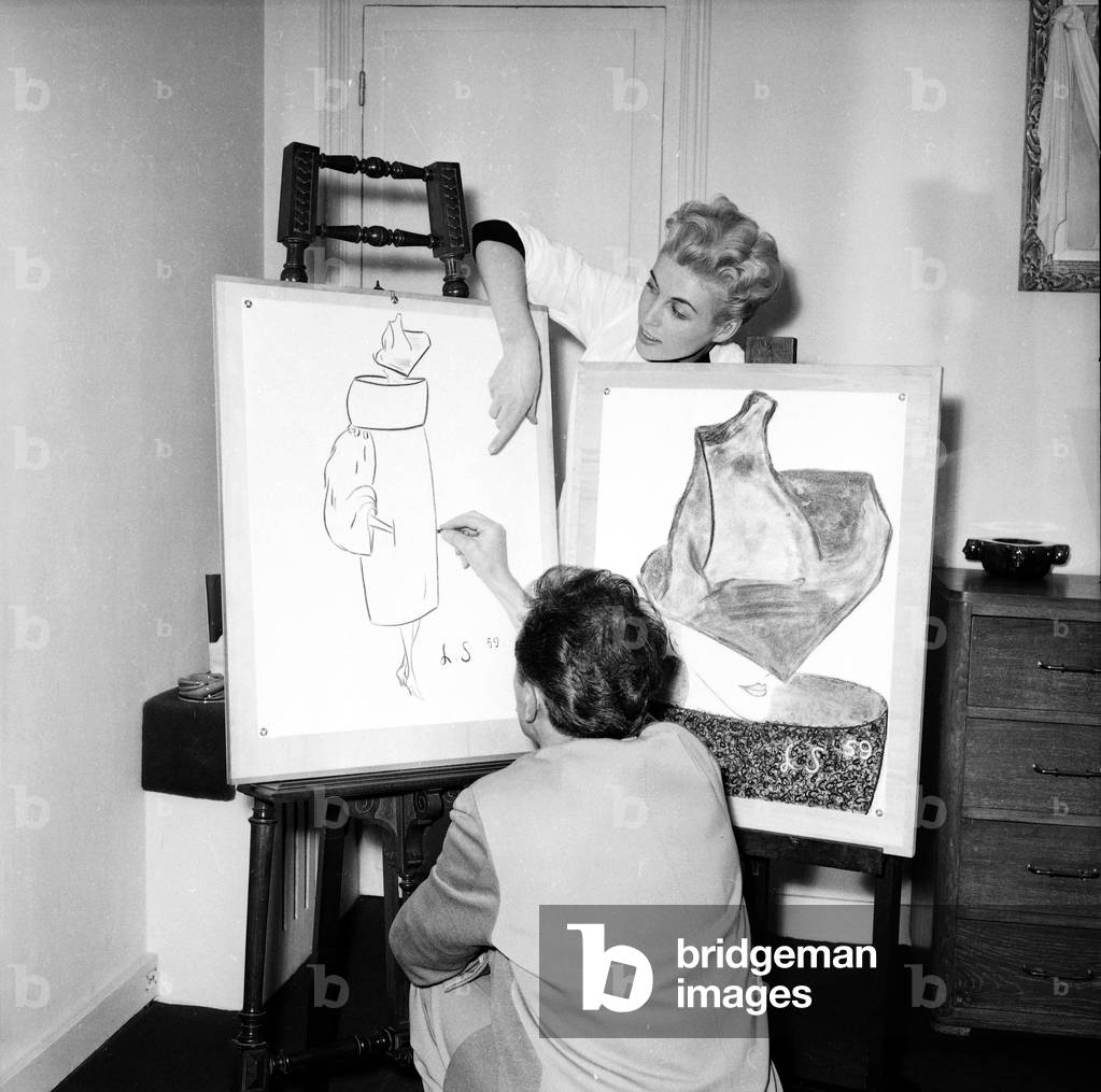 Laad Simko was the first to create a bag dresses, here shows with a sketch what will be the guideline of his new collection. The collar and sleeves of the model he presents to us are Vanchon shaped. July 18, 1958 Neg: D60014 (b/w photo)