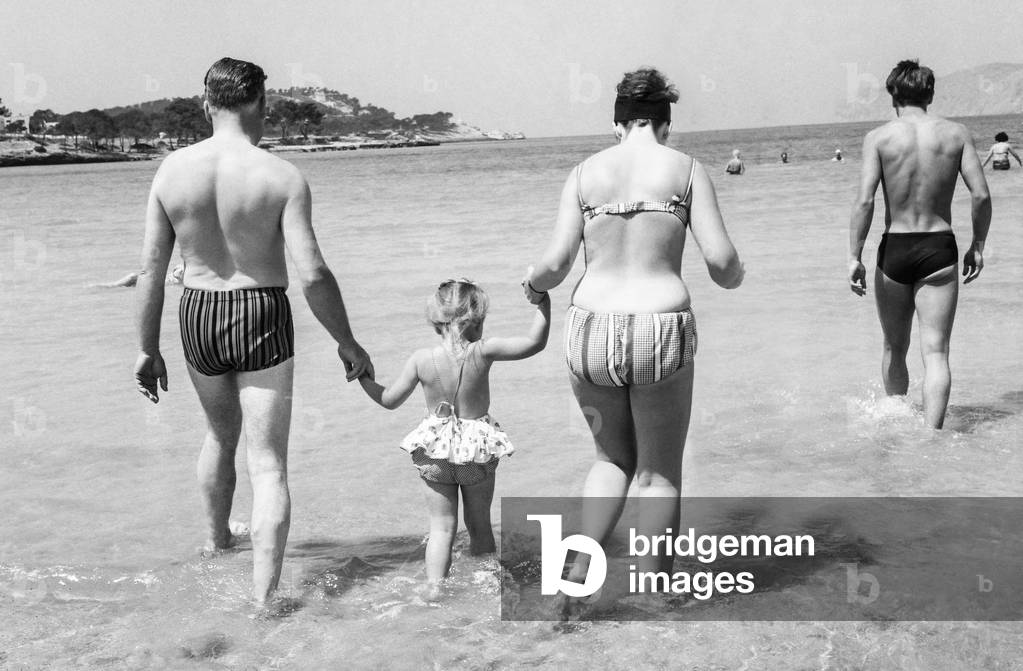 Parents with their child bathing in the sea, France, June 2, 1963 (b/w photo)