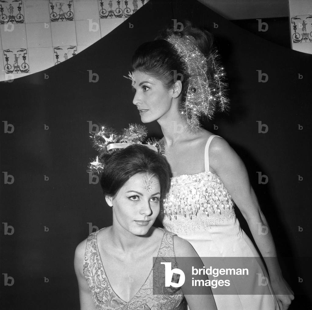 These Two Pretty Women Ready For A New Year And Wearing Evening Dresses With On The Forehead A “Fly” And Strings Of Hair Braids In Their Hair Cree By Desfosse On November 30, 1966 (b/w photo)