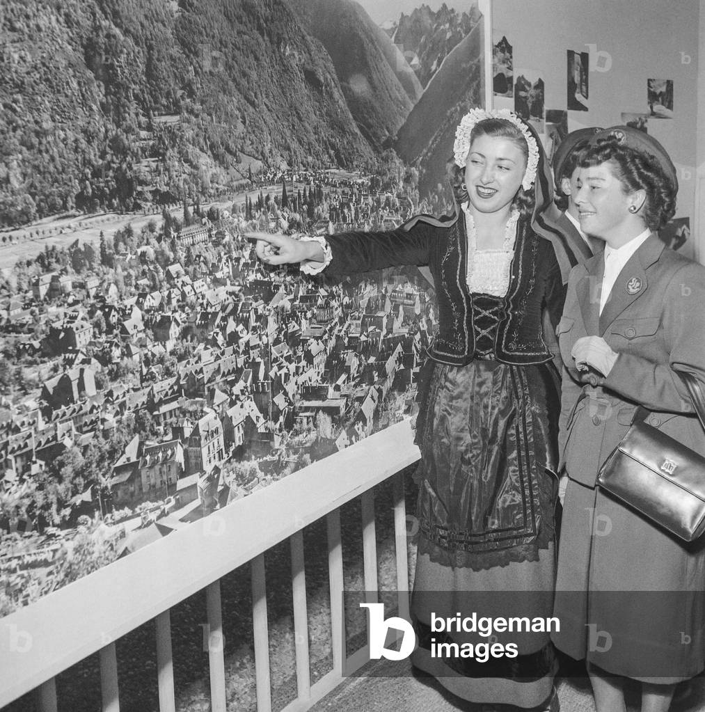 Tourism fair in Paris on October 30, 1950 : a young woman from Luchon presenting a photo of her town (b/w photo)
