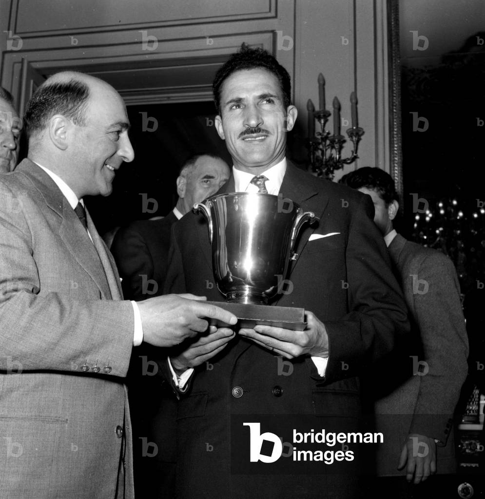 French Athlet Alain Mimoun (Winner of Marathon at Melbourne Olympic Games) Receiving A Cup From French Minister of Education Rene Billeres, Paris, February 2, 1957 (b/w photo)