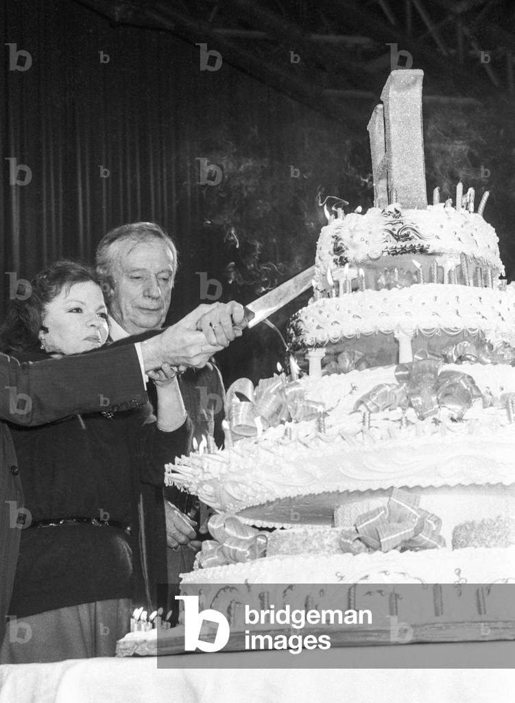 Dinner for the 160th anniversary of Hachette publishing house in Paris on March 6, 1986 : Catherine Allegret and Yves Montand cutting the cake (b/w photo)