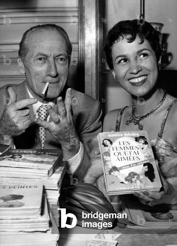 Maurice Dekobra and Dancer Fortunia Selling his Novel Les Femmes Que J'Ai Aimees, June 1, 1956 (b/w photo)