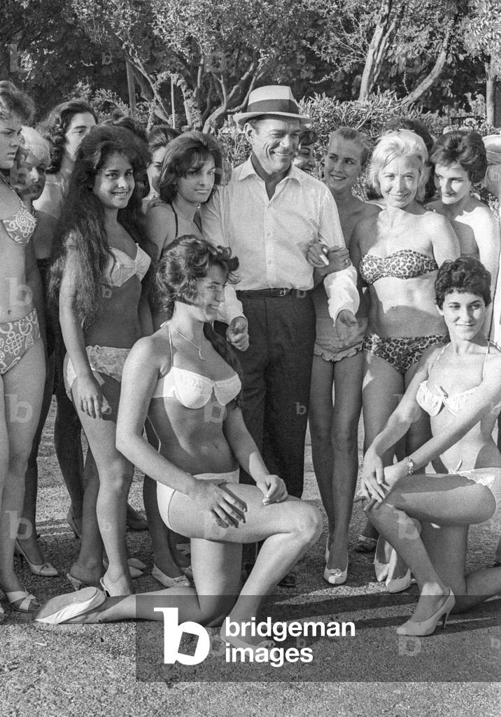 Eddie Constantine with young women on set of film 