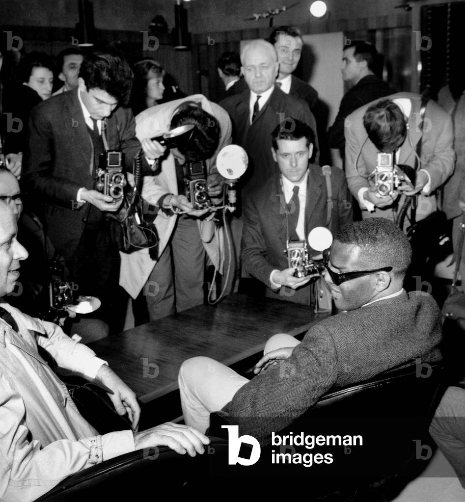 American Jazz and Blues Singer Ray Charles (1930-2004) in Paris on May 7, 1963 Surrounded By Photographs (b/w photo)