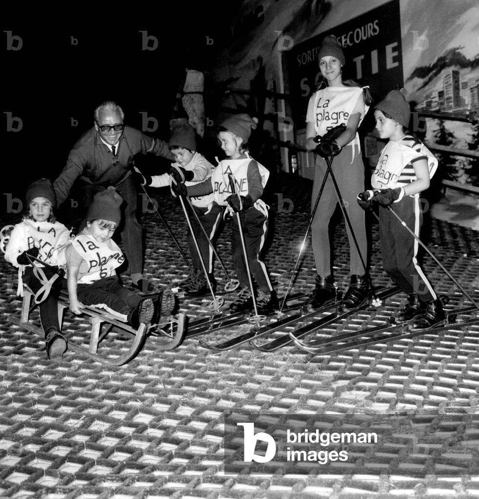 At Childhood Fair in Paris October 26, 1967 : L-R on The Sled Are Cecile Nougaro Daughter of Claudenougaro , and Pachi Godson of Luismariano . on The Skis L-R Olivier and Sandrine Drouot Children of Jeanclaudedrouot, With Marie and Charlotte Auffray Daughters of Huguesauffray. Adult Emile Allais in The Background (b/w photo)