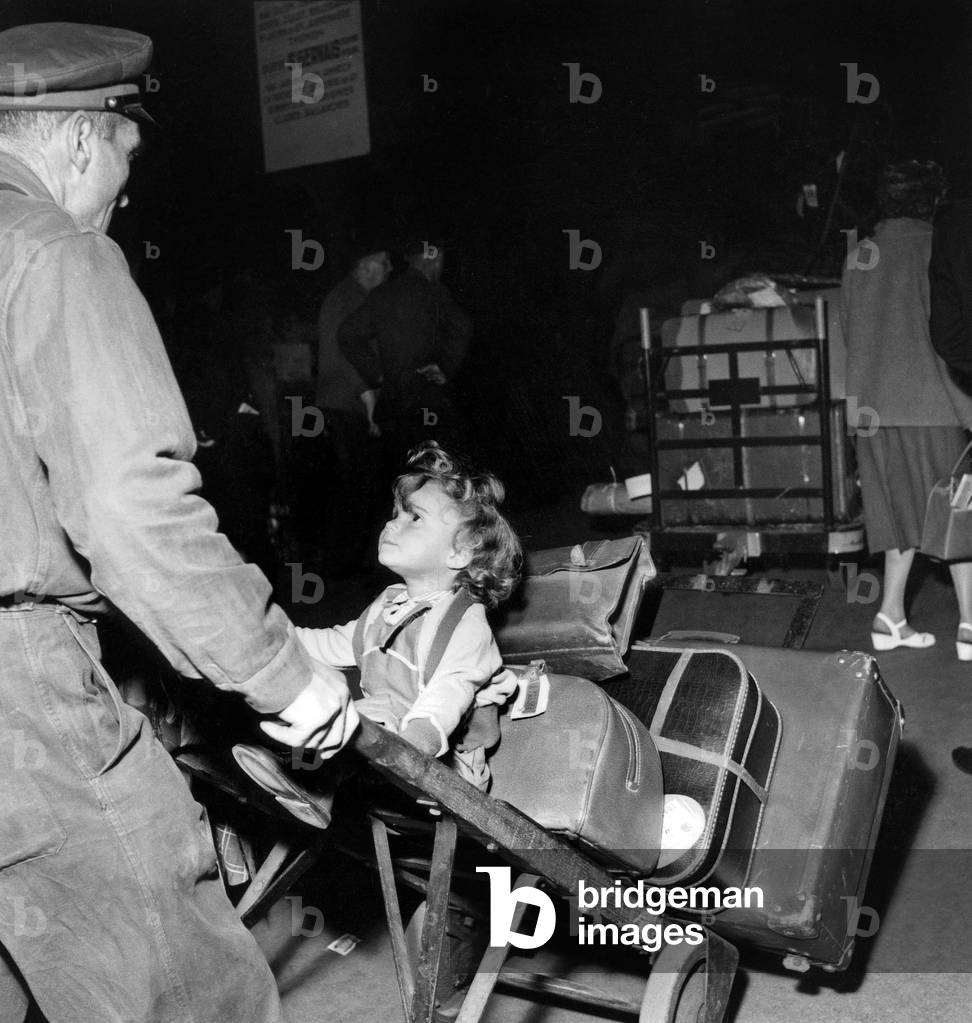 Vacation Holidays Departure at Lyon Railway Railroad Station in Paris : Little Girl Seated on Suitcase August 1, 1956 (b/w photo)