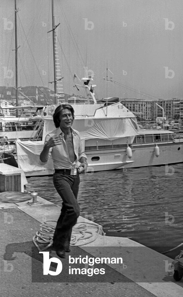 French singer Jacques Dutronc walking on the quayside in Cannes, France, July 28, 1971 (b/w photo)