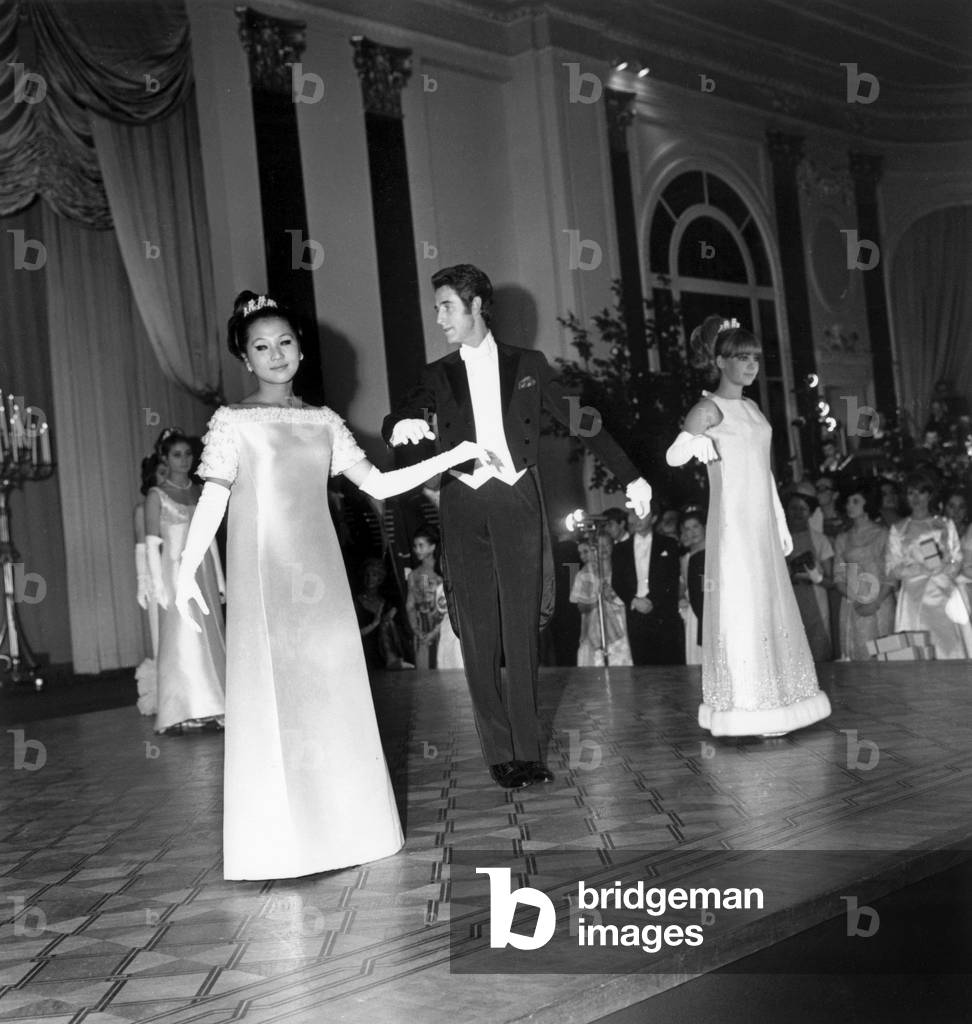 On December 19, 1965, Ball of The Debutantes in Ambassadeurs Hotel in Cannes : Jacques Chazot (Master of Ceremony), Vietnamese Princess Phuong Thao and Caroline Boyriven (b/w photo)