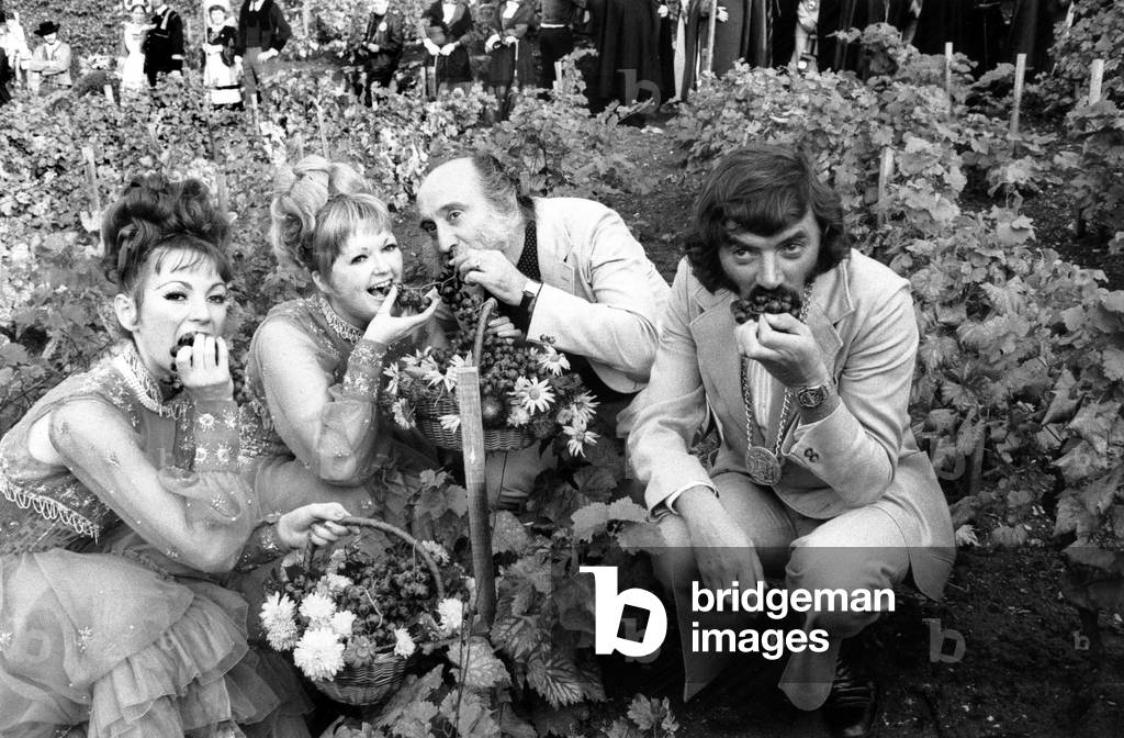 French Comics Les Freres Ennemis (Andre Gaillard Left and Teddy Vrignault Right) With Two French Cancan Dancers Eating Grapes during Grape Harvest Fair in Montmartre, Paris October 06, 1973 (b/w photo)