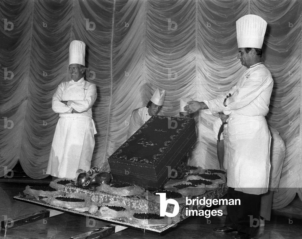 French pastry cook Gaston Lenotre and French cook Paul Bocuse presenting their creation at a party organized by Cartier, Paris, 1983 (b/w photo)