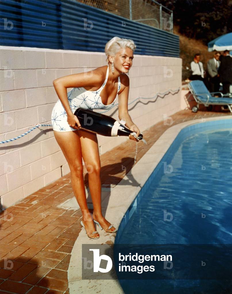 American Actress Jayne Mansfield with a bottle of champagne, near a swimming pool, 1956-1957