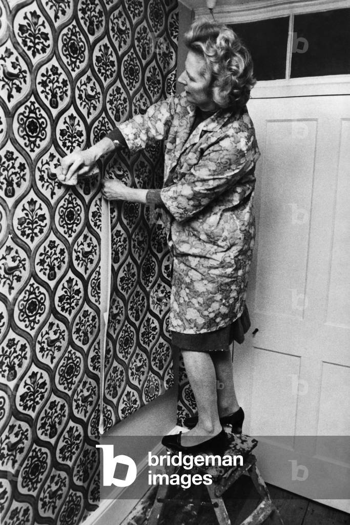 Margaret Thatcher hanging wallpaper at her country home at Scotney Castle, 23 October 1975 (b/w photo)