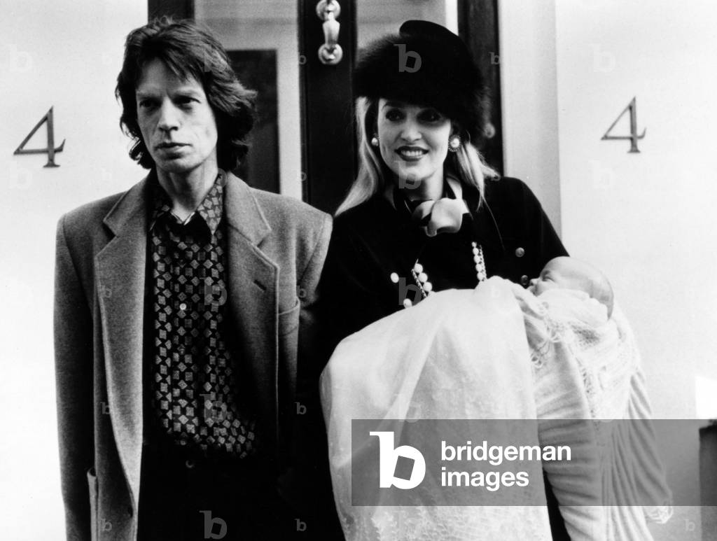 Mike Jagger And Jerry Hall At The Bapteming Of Their Child James Leroy In Front Of St. Mary Abbots Church In Kensington In Londrs November 12, 1985 (b/w photo)