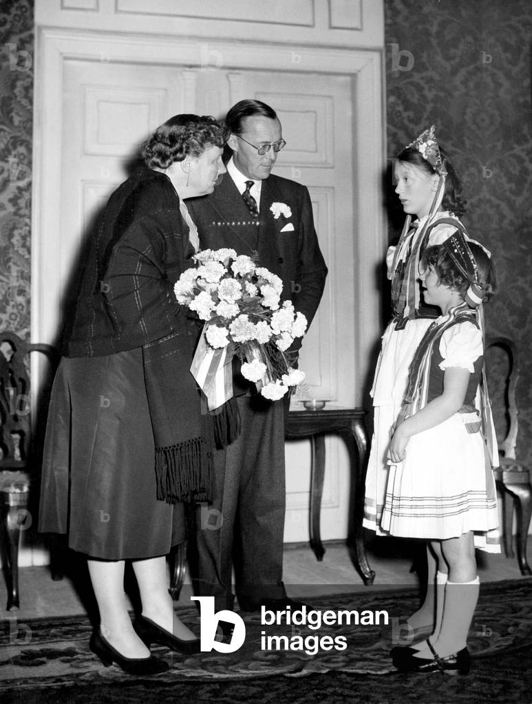 Queen Juliana of Holland and her husband Prince Bernhard of Lippe Biesterfeld at a performance of the Dutch ballet at Den Hague for the Benefit of the National Committee assistance for Hungarian people, here greeted by two Hungarian girls in the national costumes November 12, 1956