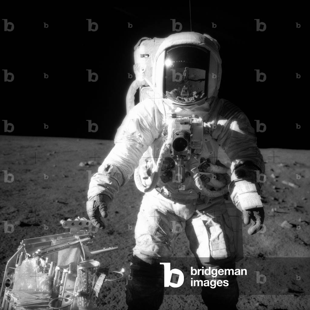 Apollo 12, November 1969 : Astronaut Alan L. Bean, Lunar Module pilot, pauses near a tool carrier during extravehicular activity (EVA) on the Moon's surface. Commander Charles Conrad Jr., who took the black and white photo, is reflected in Bean's helmet visor.