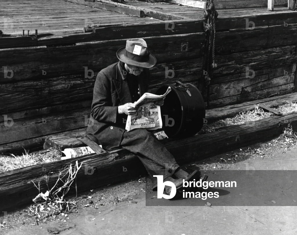 A hobo reading paper in New York in the 30's