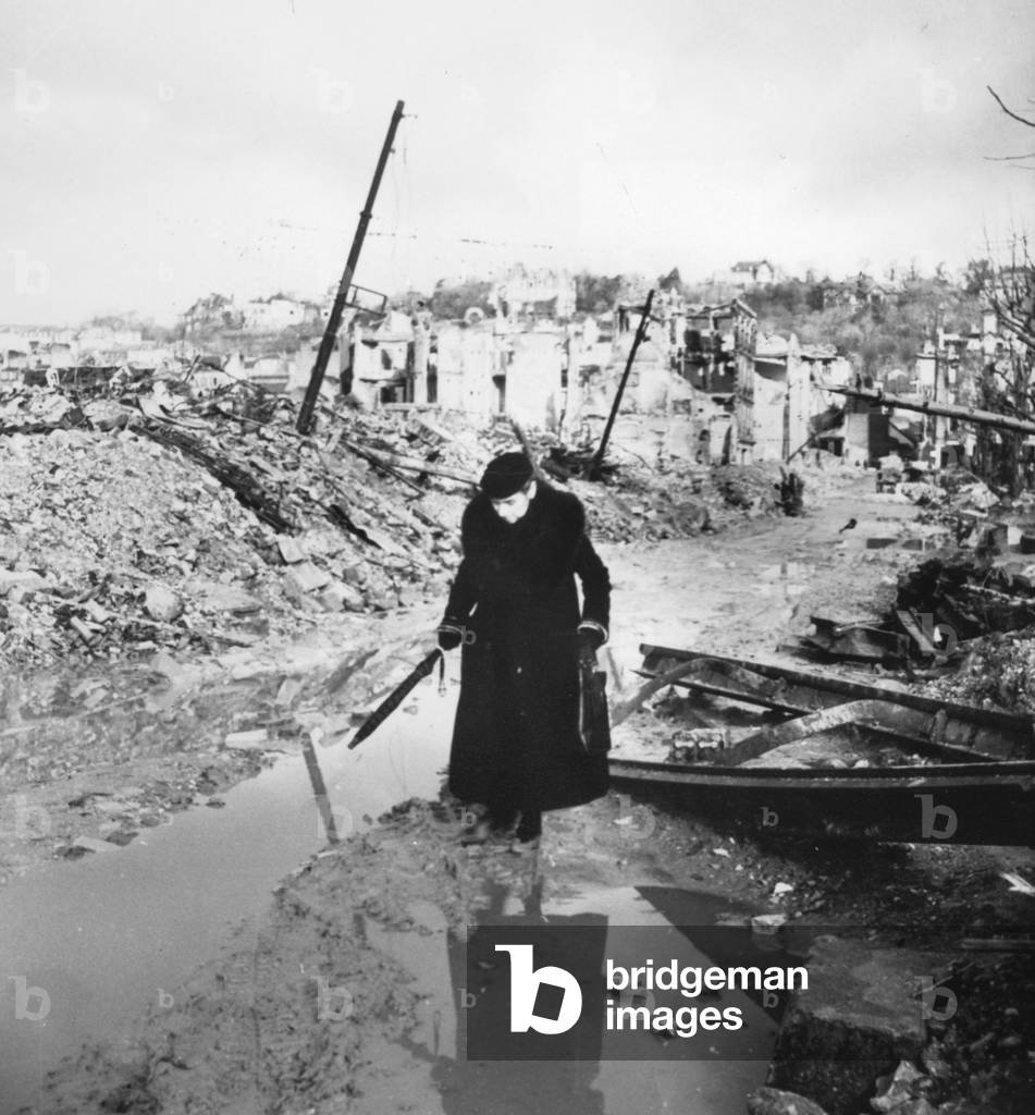 Old woman in ruins of a a town destroyed by bombings 1944