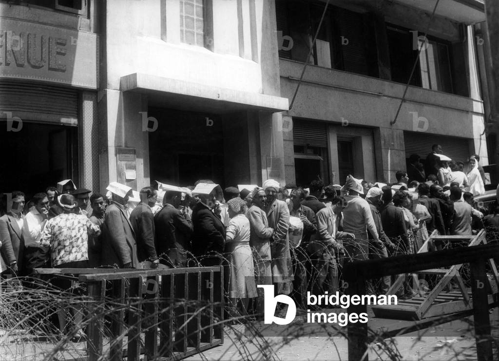 Algerians and Europeans standing in a queue outside the centre of giro cheques in Algiers, Algeria, June 22, 1962