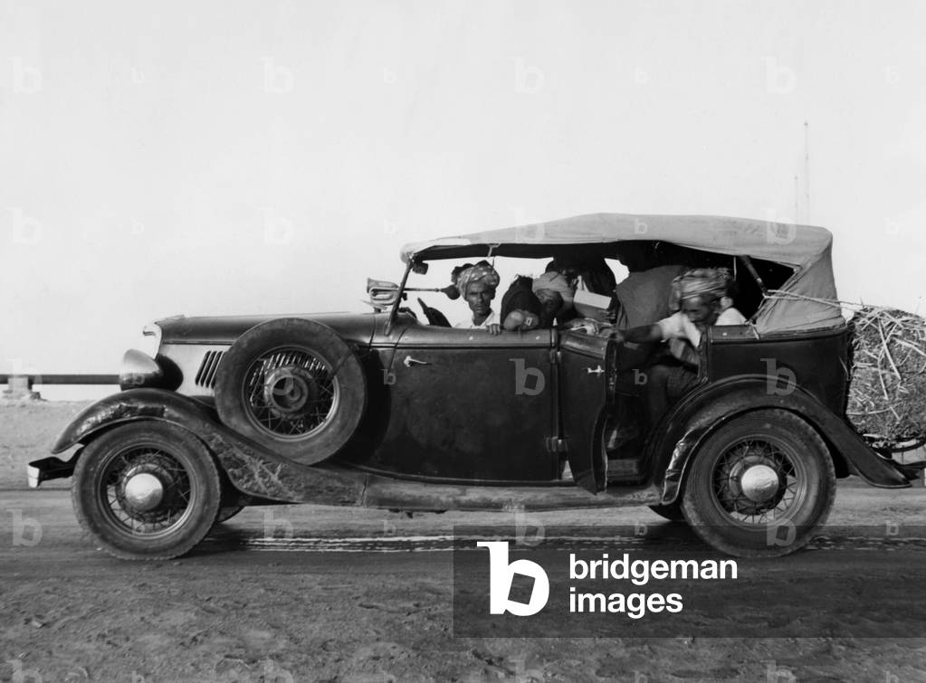Men travelling in a car with luggages, on a main road connecting Massawa to the Sudan and Abyssinia. Eritrea, Africa.