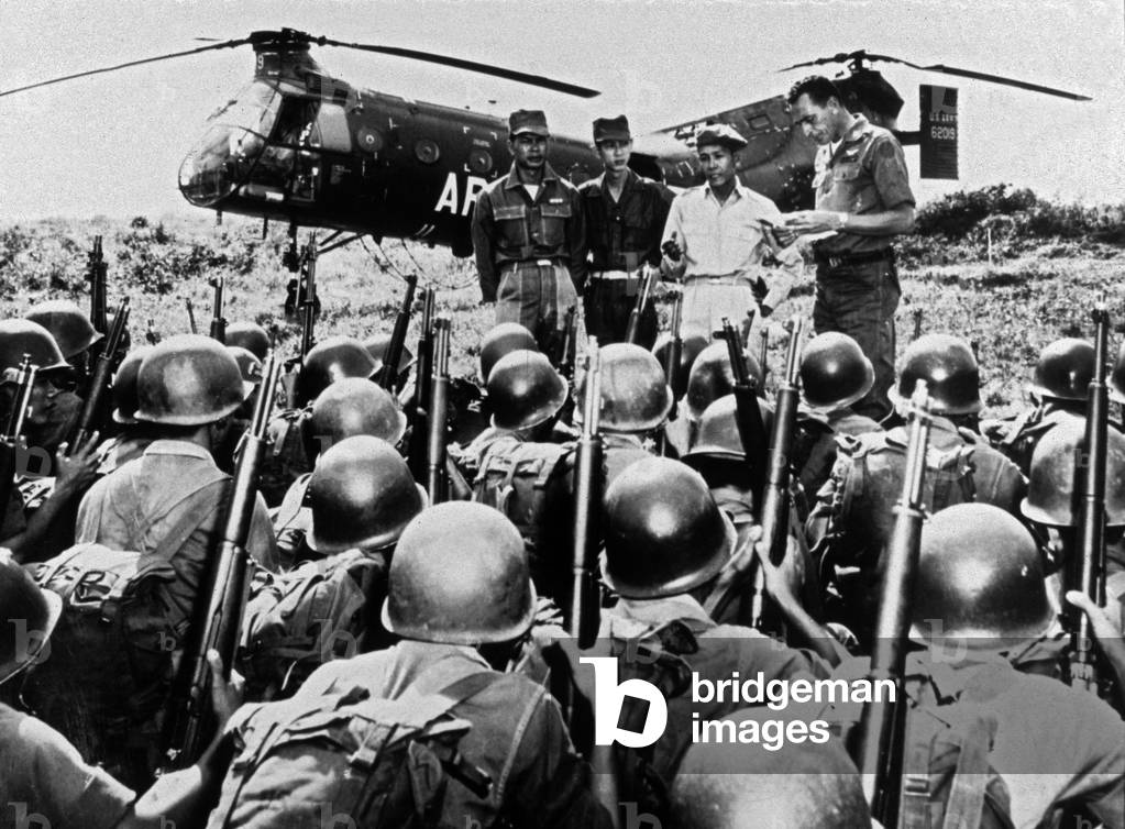 Vietnamese soldiers received instructions from American officer Richard Parsons (r) March 1965 in the south during Vietnam war helicoptere helicopter (in the background is US Army H-21C Shawnee troop transport helicopter)