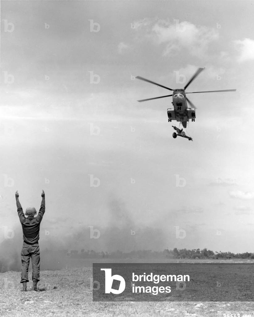 Arriving at a forward area, a U.S. Air Force CH-30 helicopter carrying a 105mm howitzer is directed in for a landing. The artillery piece, which was in a rear area and was needed by U.S., Vietnam, and Australian troops, was airlifted to the front in a mat Vietnam, 1966