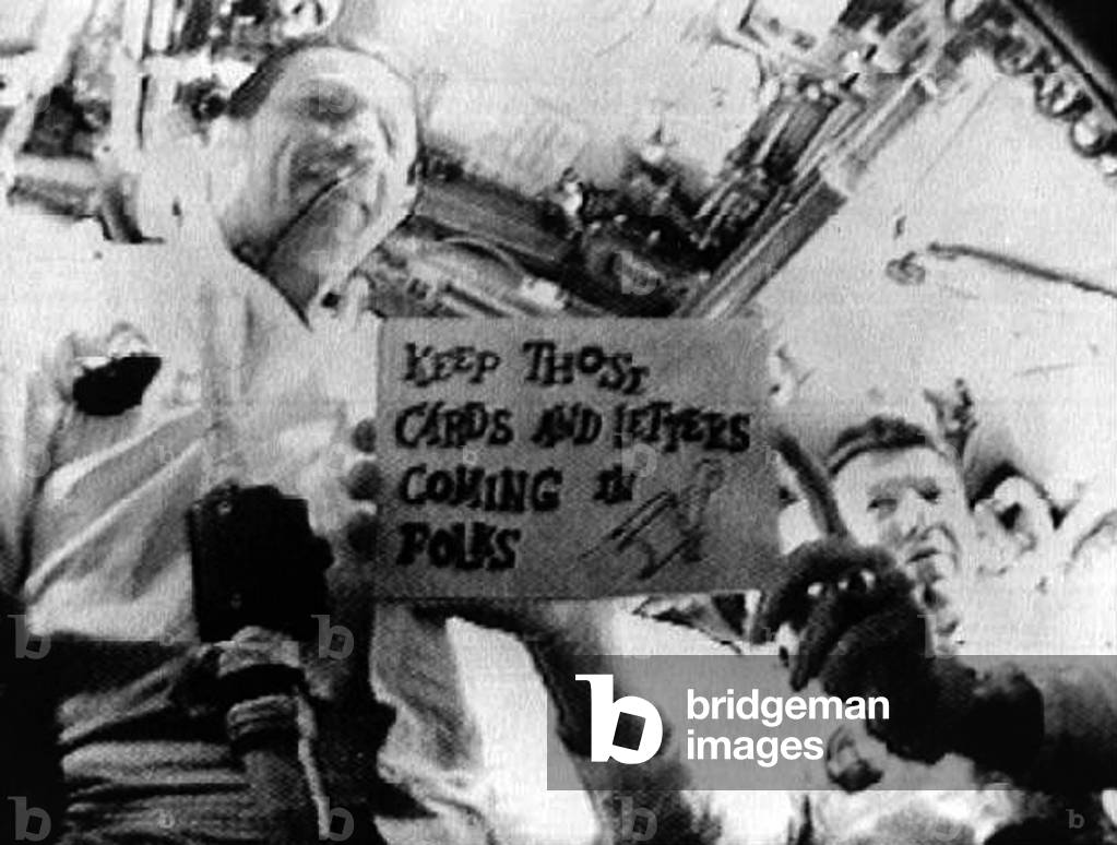 Apollo 7 mission on October 14, 1968 Astronauts F. Eisele (l) and Walter M. Schirra Jr (r). It's the 1st live television transmission from space. Schirra is holding a sign which reads 