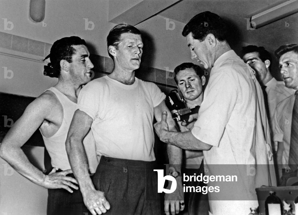 doctor vaccinating football player Peter Backer, with Mac Kay, Allen, Norman and Medwin, against the flu with compressed air gun October 20, 1962