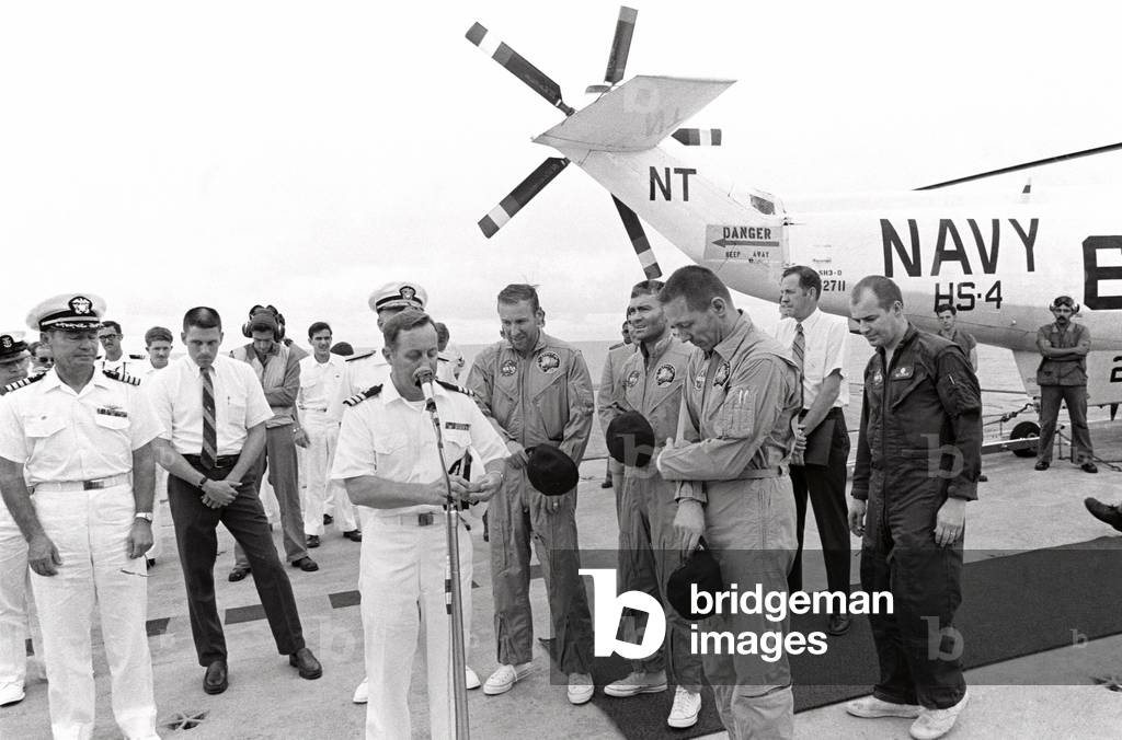 Commander Philip Eldredge Jerauld (at microphone), ship's chaplain for U.S.S. Iwo Jima, offers a prayer of thanks for the safe return of the Apollo 13 crew members soon after they arrived aboard the recovery ship. Standing in the center of the picture, from the left, are Astronauts Jim Lovell Jr., Commander; Fred W. Haise Jr., Lunar Module Pilot; and John L. Swigert Jr., Command Module Pilot. The Apollo 13 Command Module 