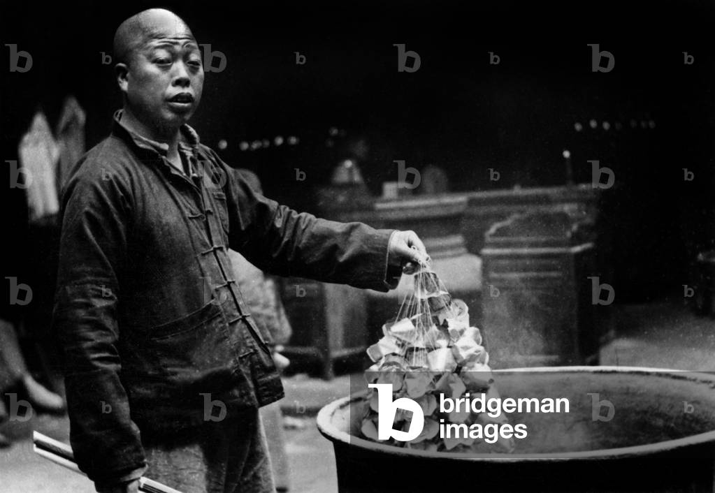 Chinese New Year, February 8, 1951: in China a man burns paper money (he rises up the sky so that the dead can recover it and live better)