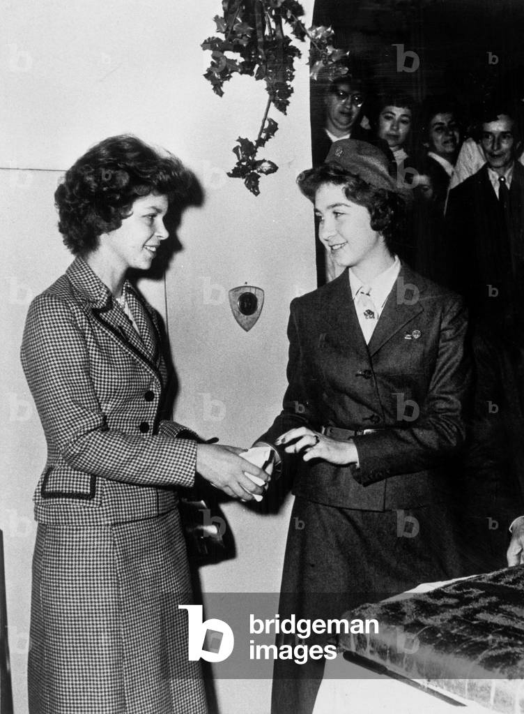 Princess Sophia of Greece , wearing uniform, giving some cake to her sister Irene January 02, 1958