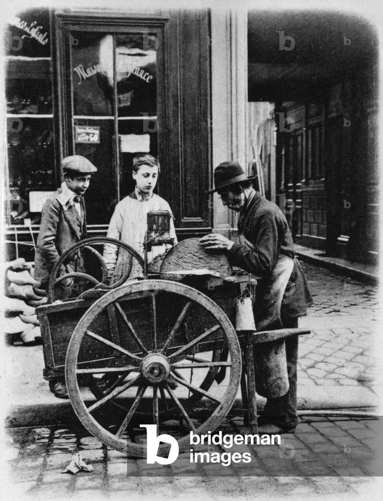 Man sharpening knives with a grindstone, in astreet, c. 1900, France