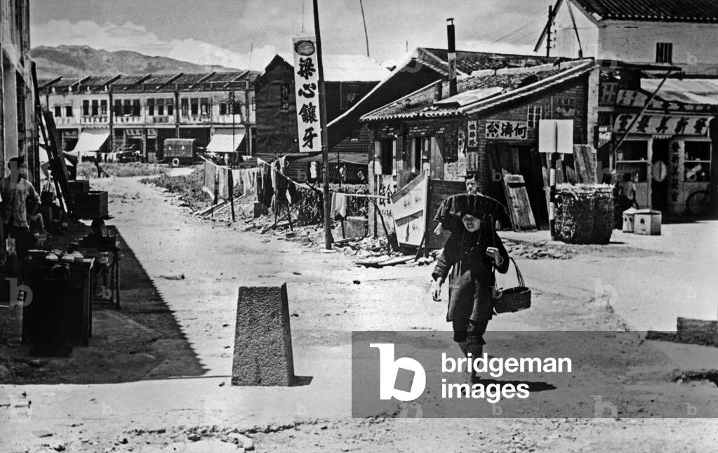 The village of Sha Tau Kok crosses through the border between the People's Republic of China (right) and the English colony of Hong Kong (left) Hakkas women (umbrella hat) c.1950