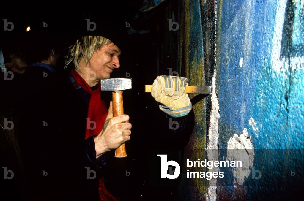 Man with a hammer and a chisel at the fall of Berlin's wall, 1989 (photo)