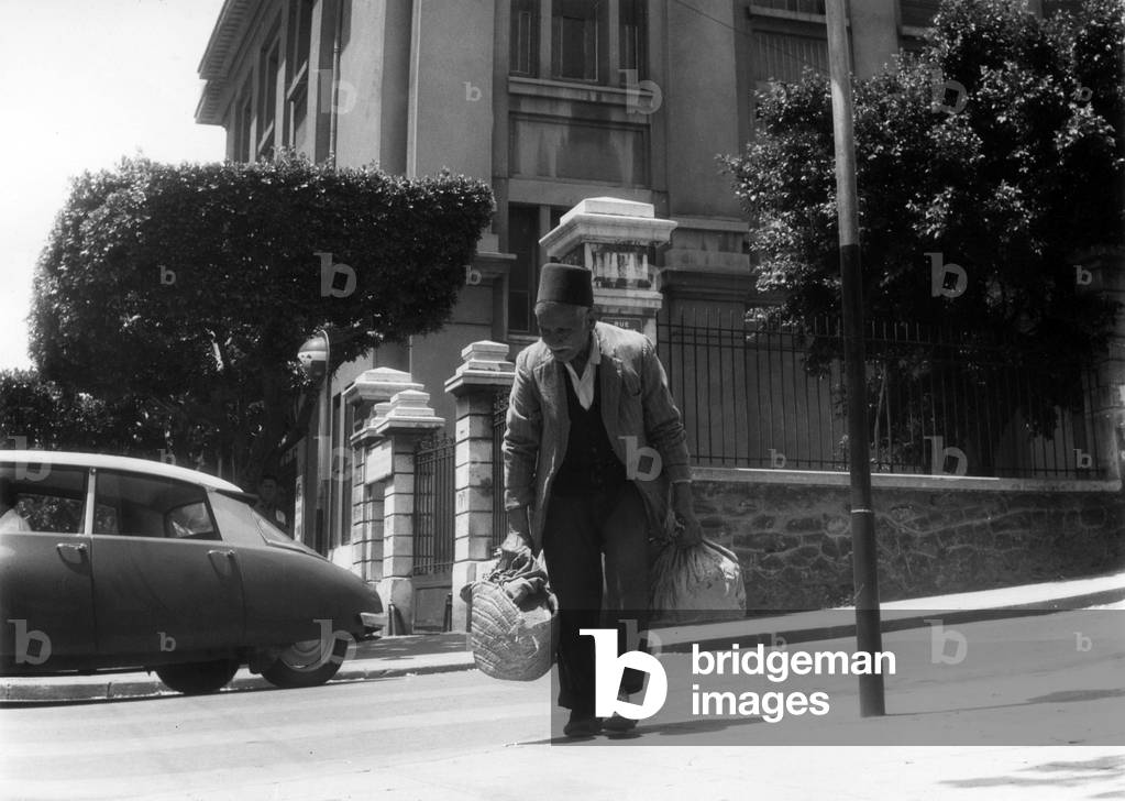 Algerian man with baskets in a street in european area in Algiers, Algeria, June 22, 1962