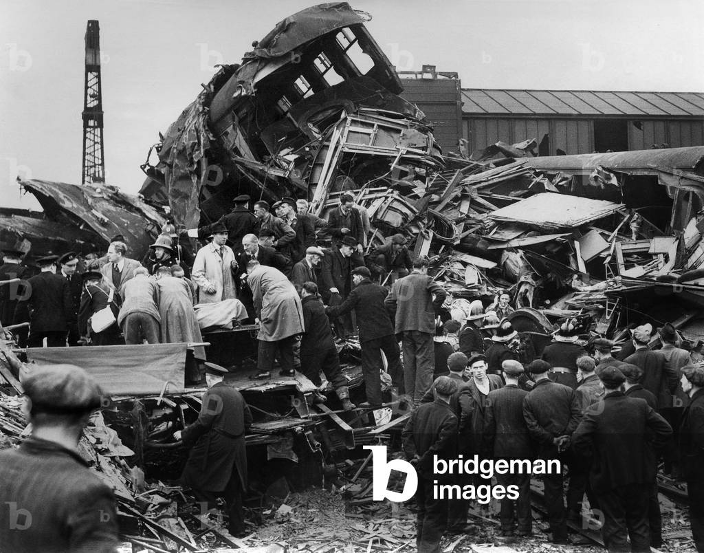 Train crash in the tube : the wreckage of coaches at Harrow and Wealdstone station, with civil defense workers helping. October 8th, 1952. London, England.