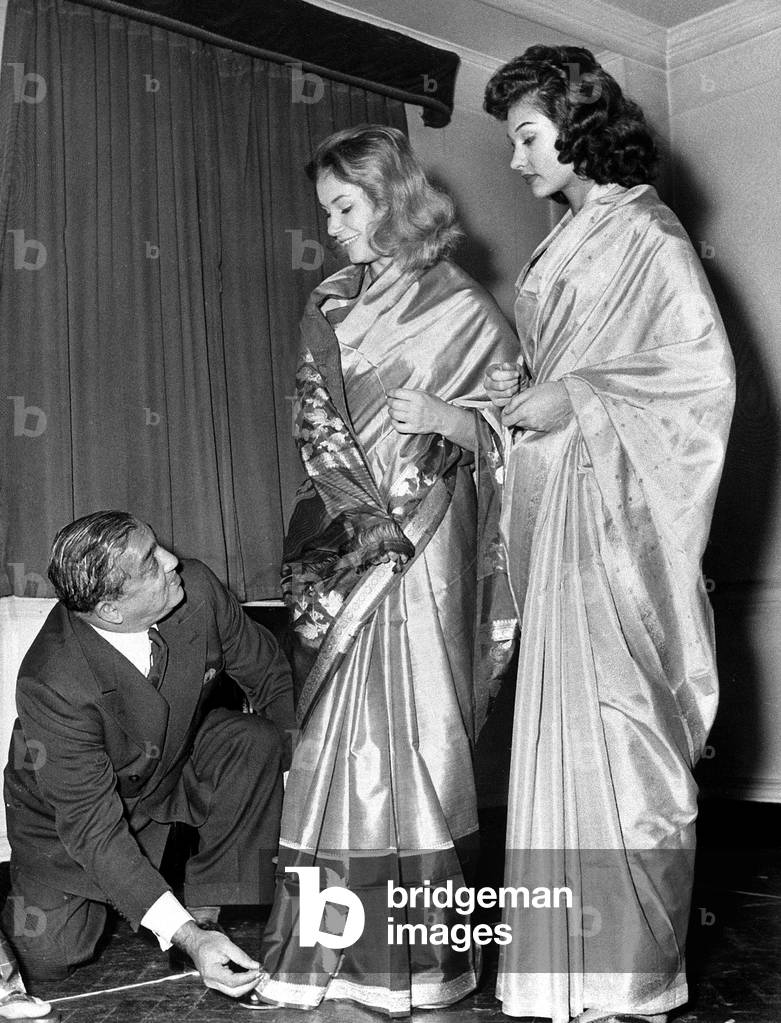 Indian maharaja of Boroda Baroda straightens himself the pleats of the saris worn by two English young women Penelope Horner (l) and Julie Shearing (r) October 24, 1958
