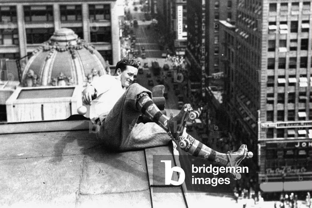Man making roller skate on the roof of a building, he's going to fall, 30's