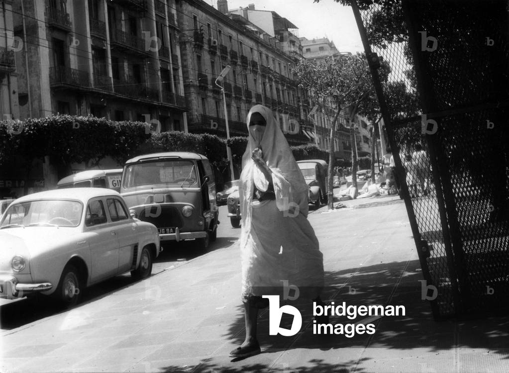 Veiled algerian woman in a street in european area in Algiers, Algeria, June 22, 1962