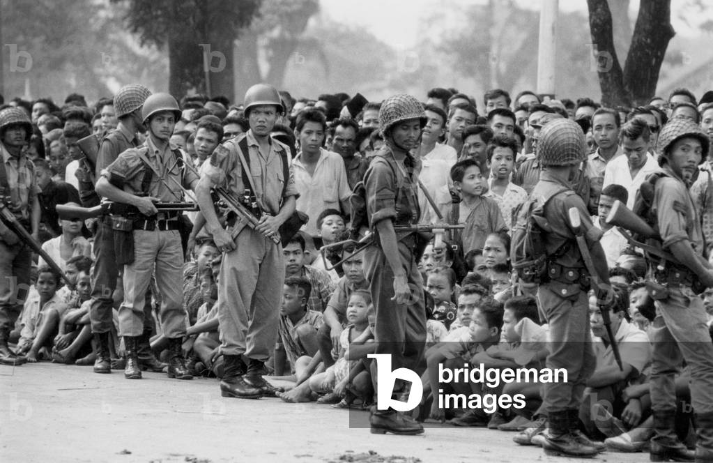 Military parade to celebrate 17th anniversary of Indonesia independance. Crowd is sitting outside official residence in Djakarta on August 17, 1962