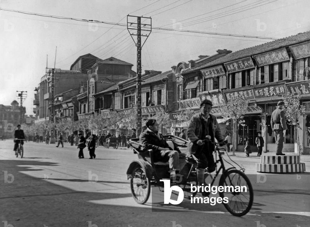 China: The wide streets of Hankow have few buses and cars. The policeman (right) wearing a mask is the one to smooth cycling traffic and avoid occasional traffic jams caused by trolleys 1946-48