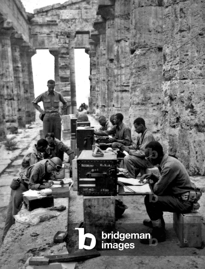 A makeshift office set up between the columns of the Greek temple of Neptune, Italy, 22nd September, 1943 (b/w photo)