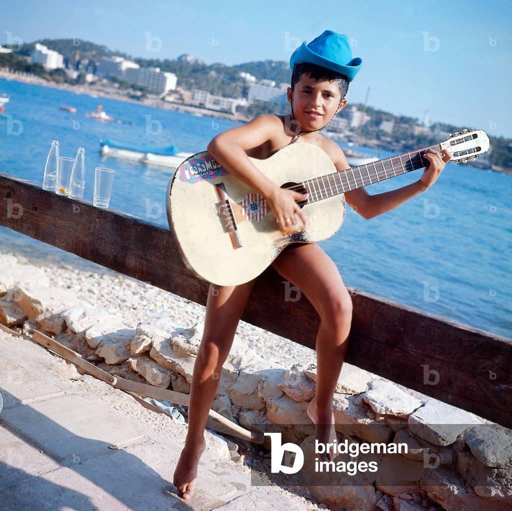 Child playing guitar in Majorca in the Balearic Islands August 1972