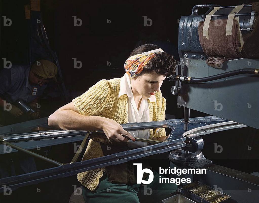 A girl riveting machine operator at the Douglas Aircraft Company plant joins sections of wing ribs to reinforce the inner wing assemblies of B-17F heavy bombers, Long Beach, Calif. Better known as the 