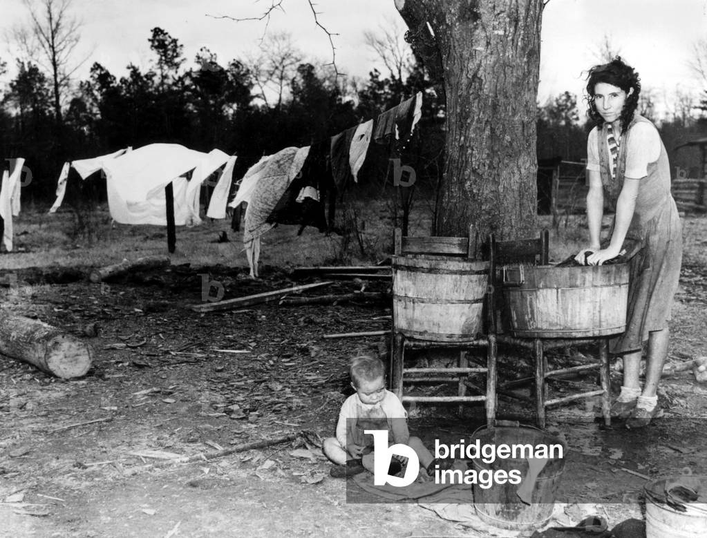 Economic crisis in USA in the 30's : in North Carolina, a woman doing the washing in the garden while her child is near her
