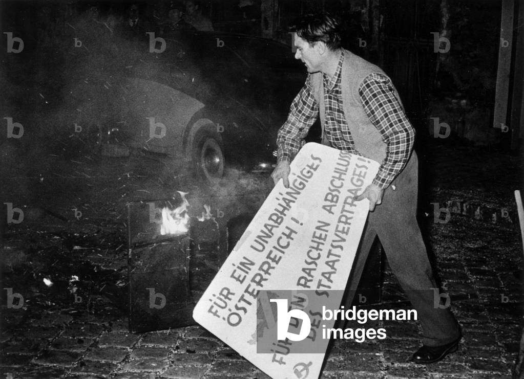 Demonstration against communism in Austria (Vienne). Here, a student throwing a communist placard on the bonfire, Vienne, 1956