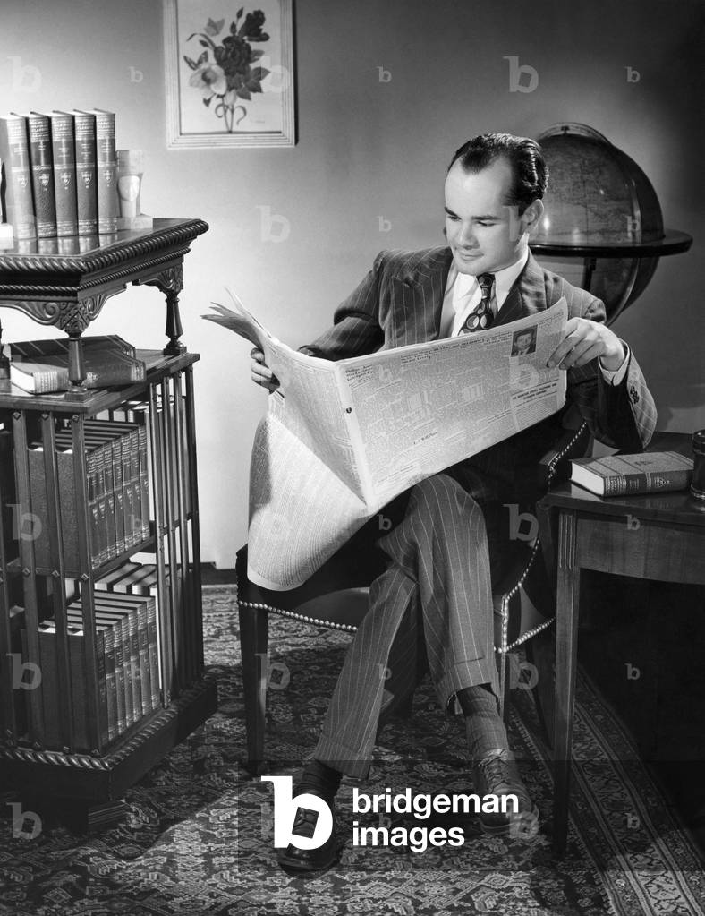 Immagine di Fotografia "Uomo di mezza età seduto su una sedia e legge un giornale", b/w