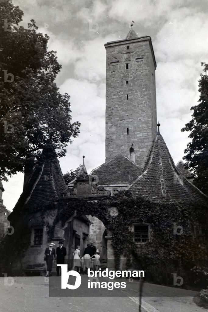 Image of Pedestrians crossing the castle gate with the big tower in