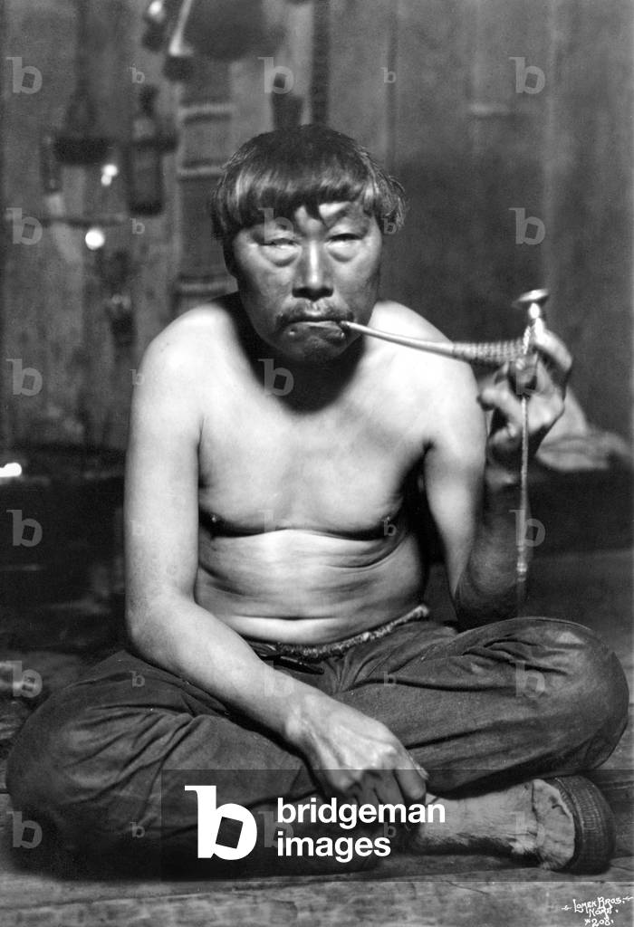 Image of ALASKA ESKIMO MAN An Eskimo man smoking a pipe, Nome, by Lomen Brothers (fl.190834)